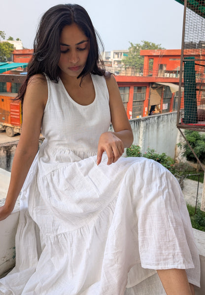 Woman in a white dress sitting on a terrace with a cityscape in the background